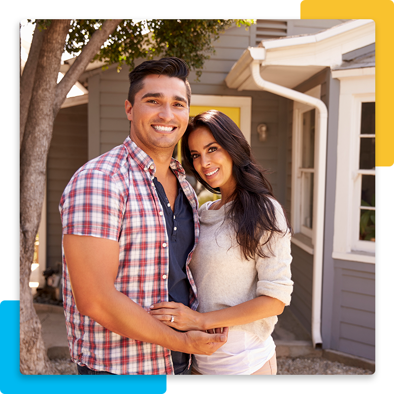 Happy Hispanic couple standing in front of house
